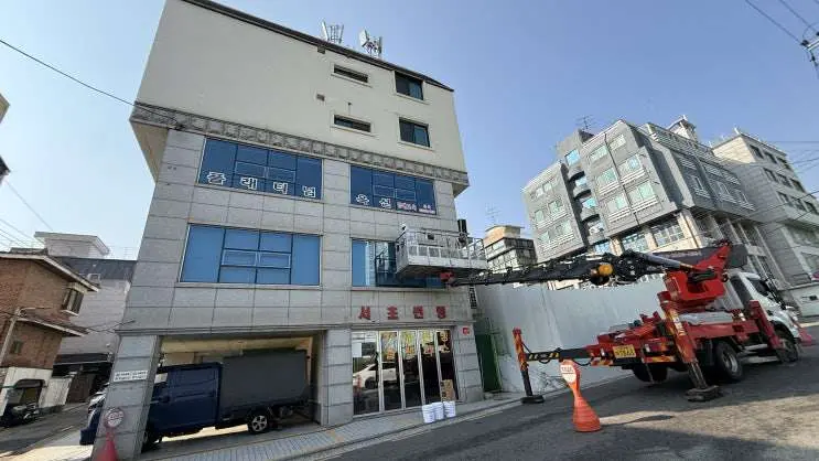 드라이비트와 석재 외벽이 함께 있는 건물 전경과 고소장비