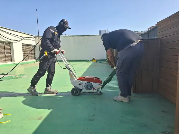 부천시 은행 건물 옥상의 두꺼운 기존 우레탄층을 기계로 철거하는 모습