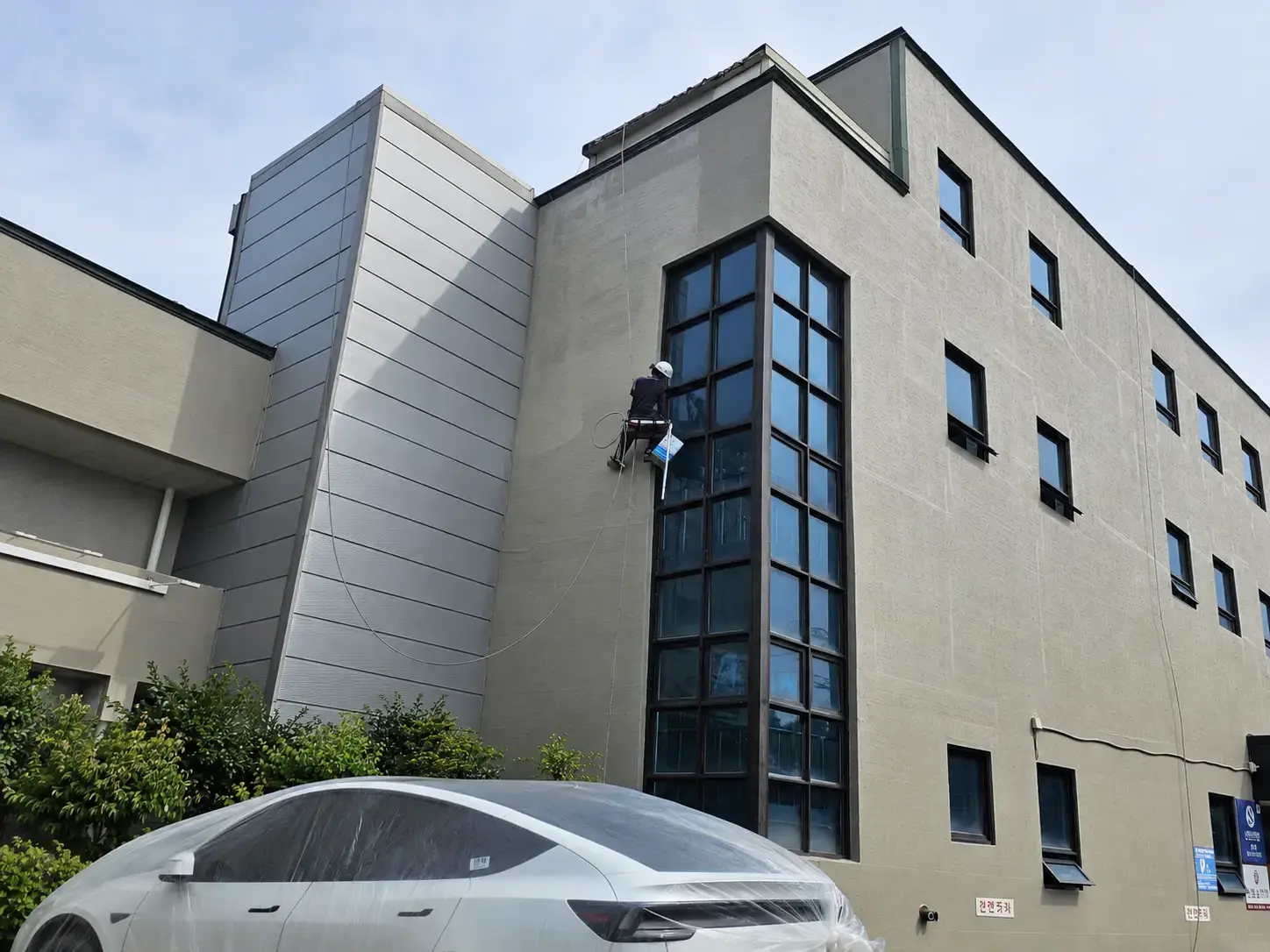 도심 건물 외벽에서 로프로 작업하는 위치가 보이는 전체 전경